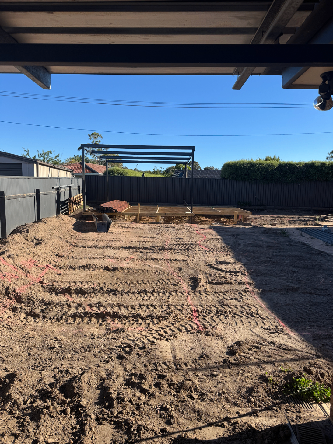 Excavated backyard with steel pergola frame and early deck construction