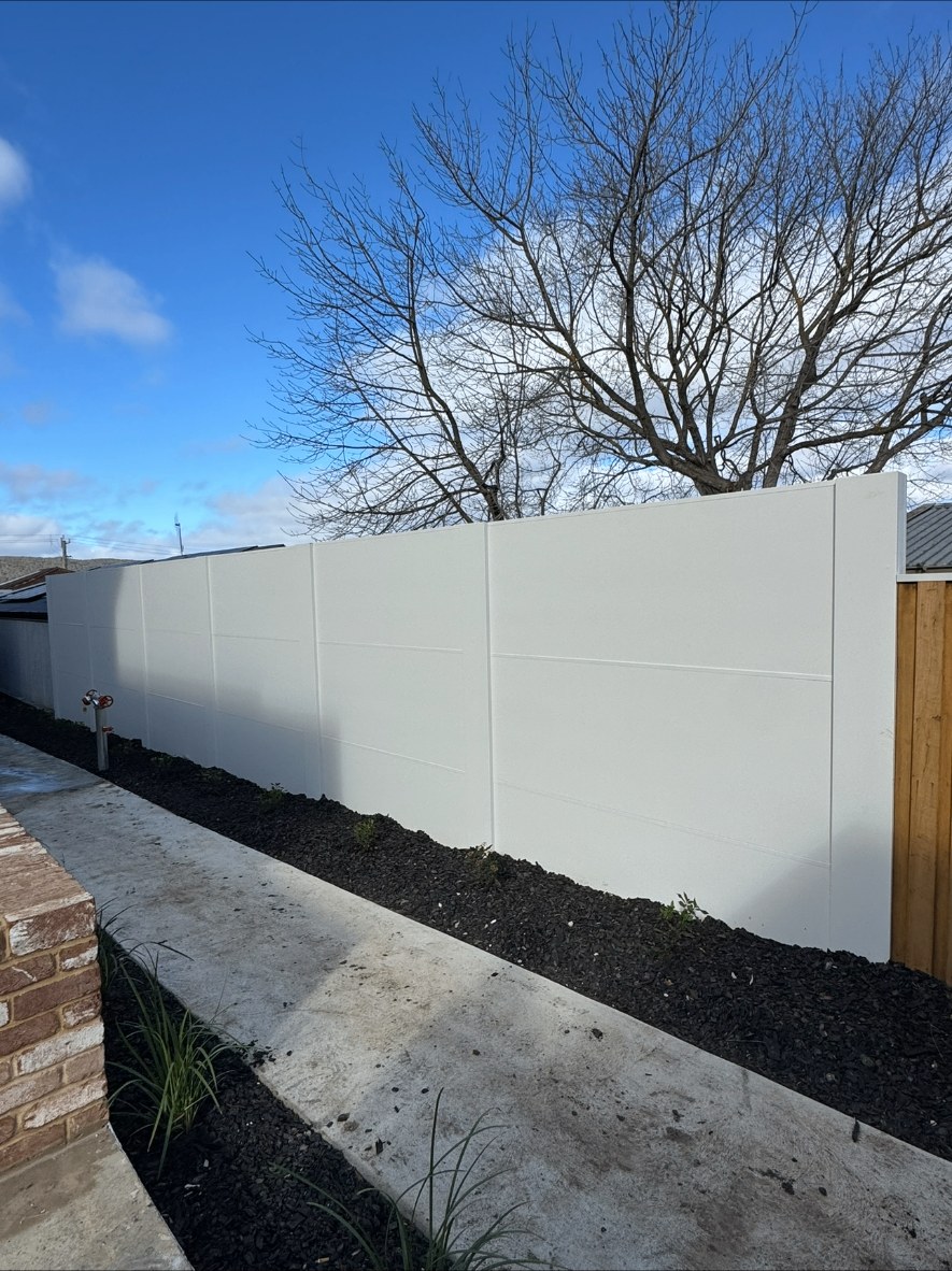 Rendered white boundary wall with black mulch garden bed and concrete path