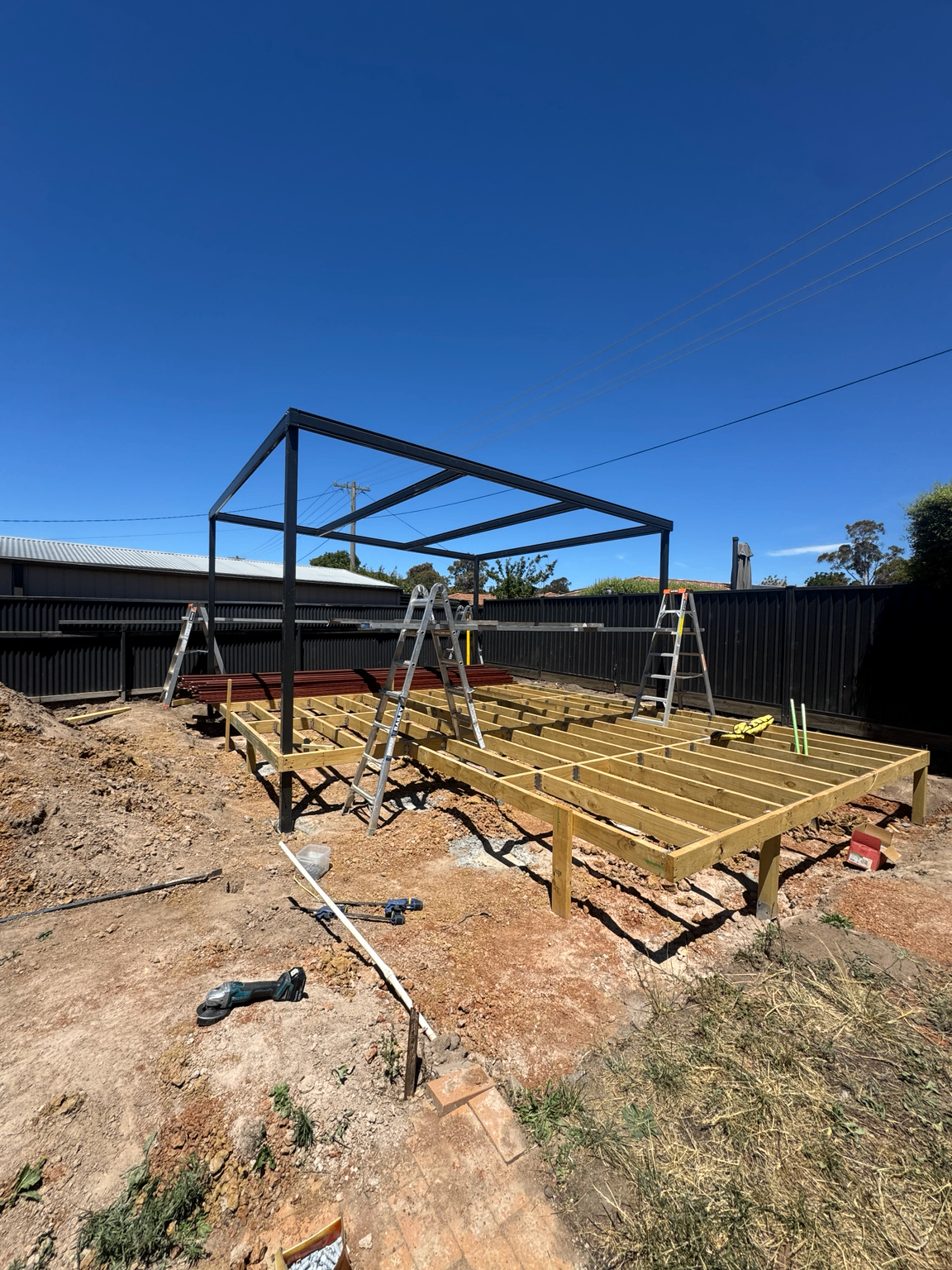 Treated-timber deck framing beneath a steel pergola structure
