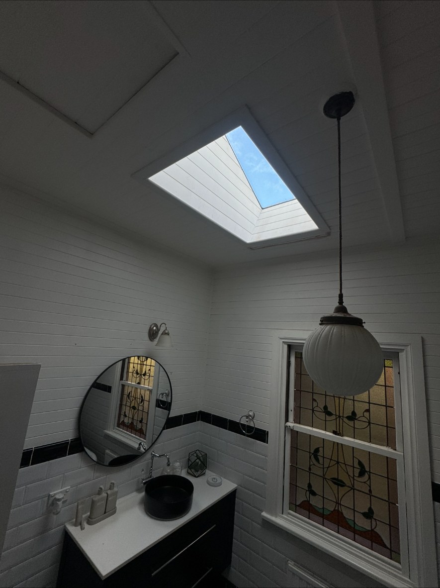 Bathroom with a new skylight above tiled walls and lined ceiling