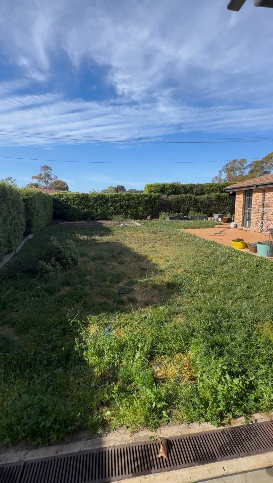 Canberra backyard before construction — patchy lawn and small paved patio